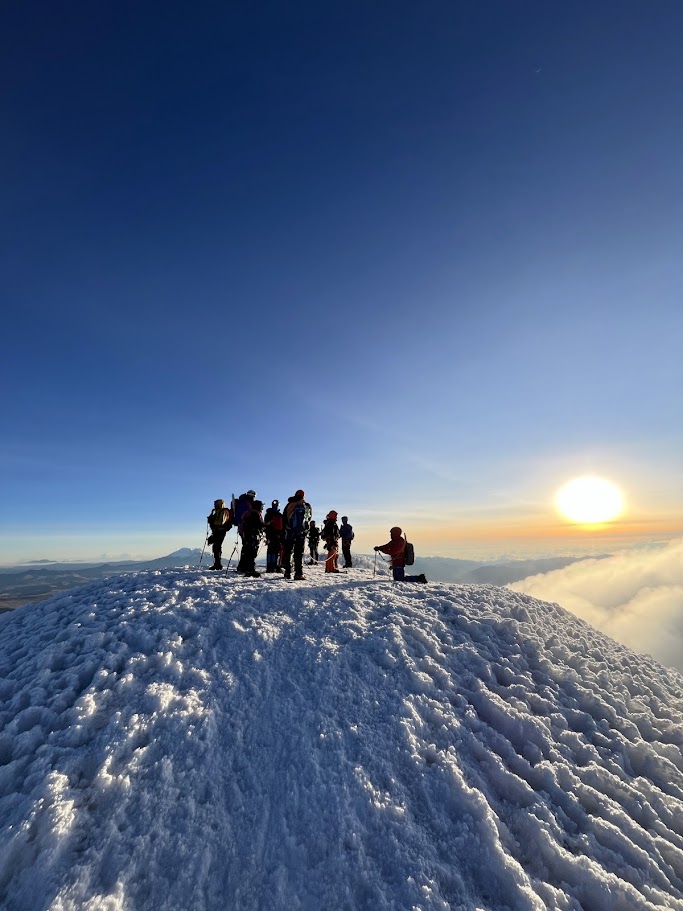 Climbers celebrating on a snowy Andean summit at sunrise